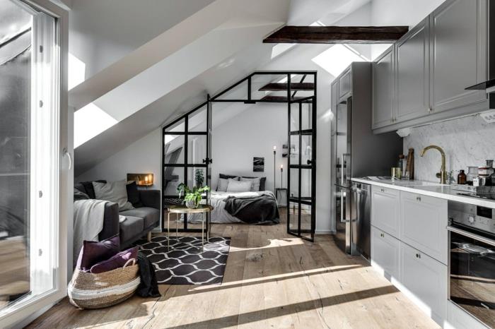 malý podkrovný byt, čierna sklenená kuchyňa pod svahom, drevená doska, šedé kuchynské skrinky