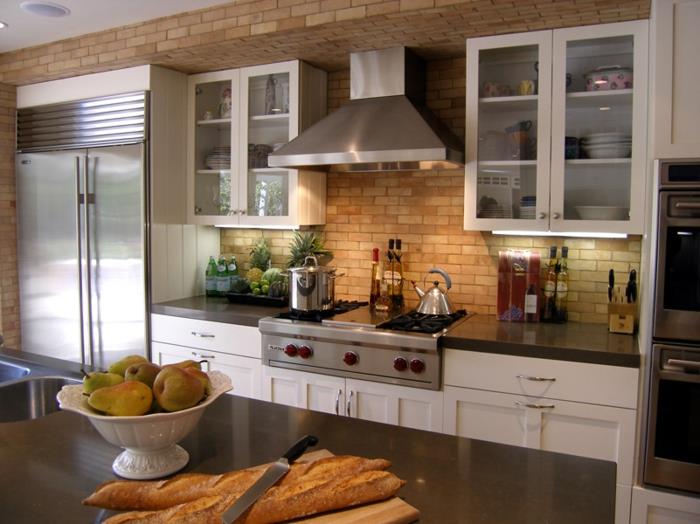vybavená kuchyňa s červenou tehlovou stenou, bielymi skriňami, skrinkami so sklenenými dverami