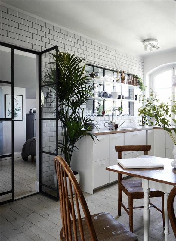čierna kuchynská strieška, biele kuchynské skrinky, drevená doska, zelené rastliny, obklad metra