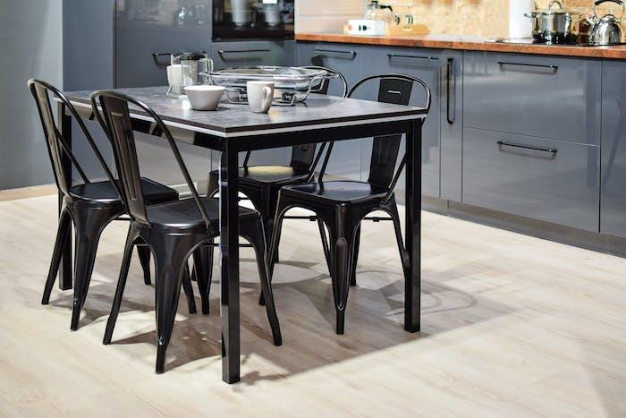 moderne vybavená kuchyňa s čiernymi stoličkami a stolom a sivou kuchynskou linkou, s drevenými pracovnými doskami, svetlou parketovou podlahou