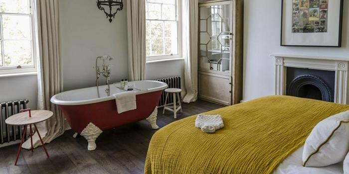 Výzdoba parížskeho bytu kúpeľňa v spálni parkety, tmavé drevené parkety, drevený a kovový konferenčný stolík horčicovo žltá prikrývka na posteľ