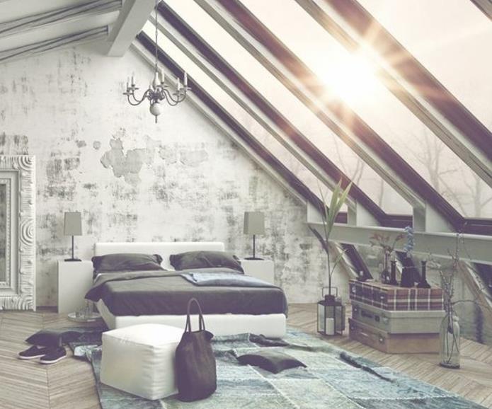 Deco sovrum under sluttningen, blå och grön matta, parkett, loft sovrum, vit säng, grå sängkläder, sliten vägg, bord, bestående av tre vintage stammar överlagrade, takfönster, ljuskrona, stor spegel