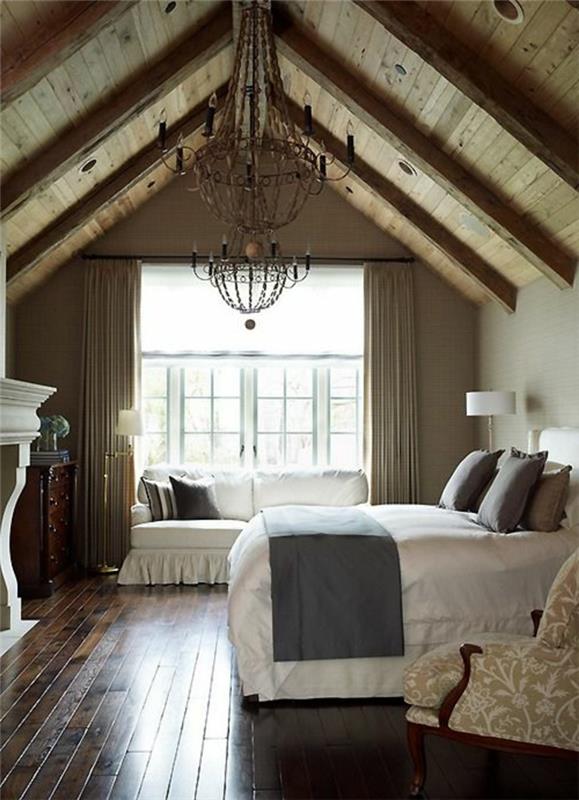passa upp. träparkettgolv, säng, vita sängkläder, grå kuddar och sängklädsel, vit soffa, vintage hängande lampa, öppen spis med sluttande tak i trä