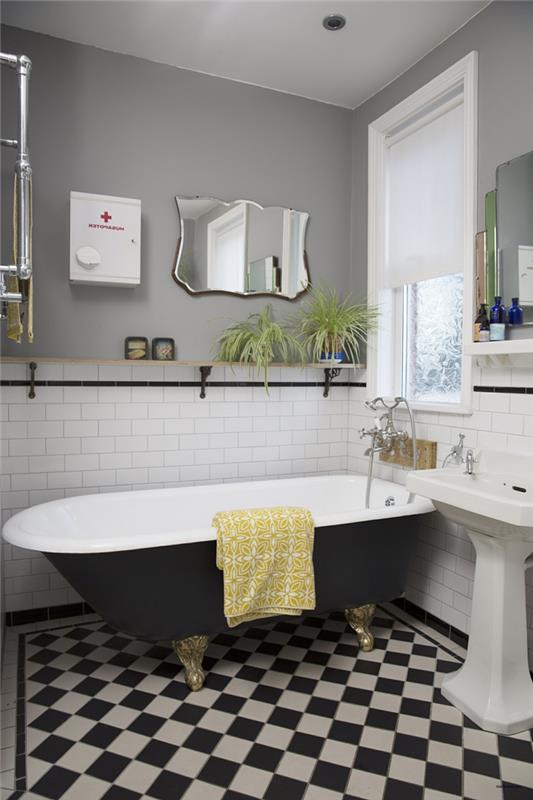 svartvitt badrum, badkar i gjutjärn, rutiga plattor, art deco -spegel, antikt handfat, grå vägg