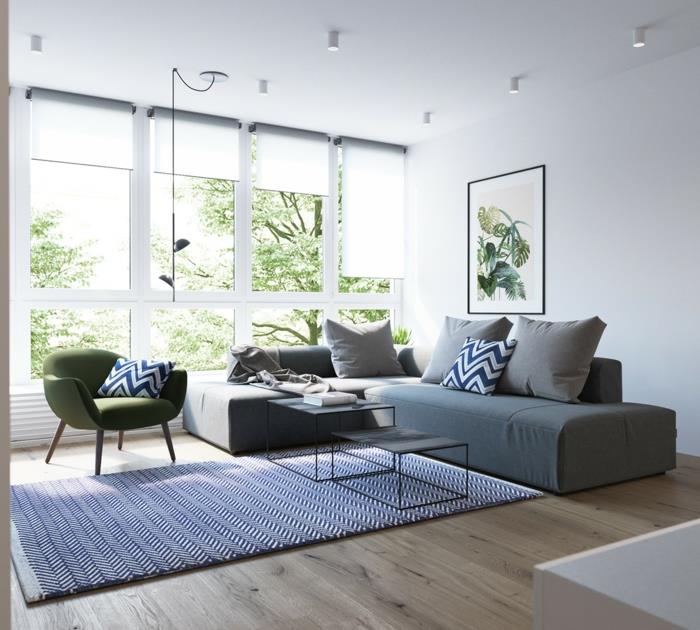 Škandinávsky nábytok, sivá sedačka a zelené kreslo, biely a modrý koberec, svetlé parkety, výhľad na zelenú krajinu