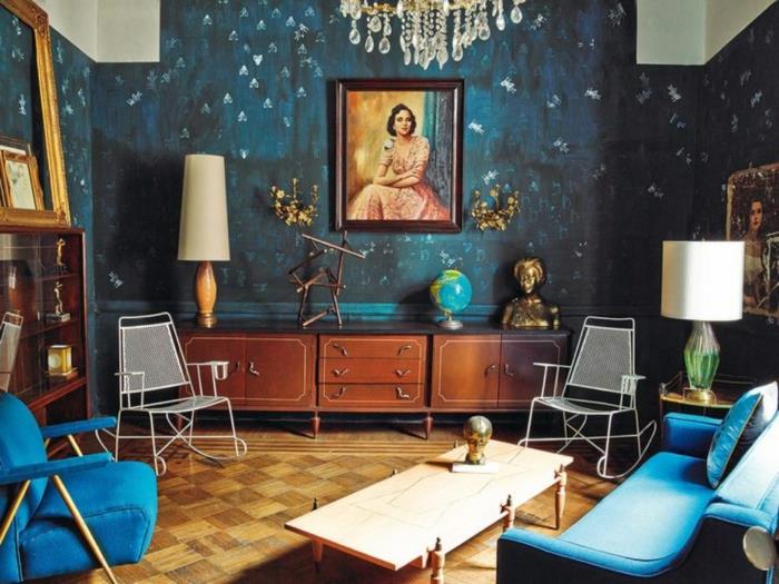 malá umelecká obývačka, modrá pohovka a kreslo v štýle polovice storočia, nízky príborník, staré podlahové lampy, strapcová stropná lampa