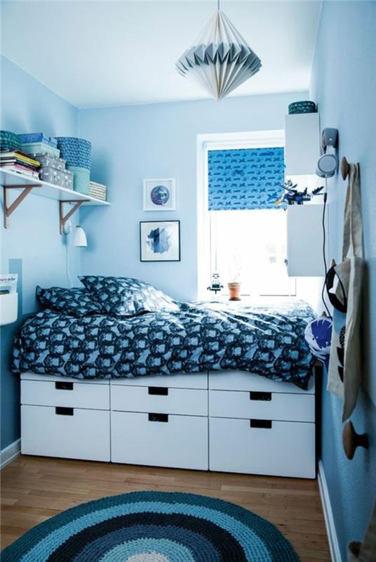 zariadte spálňu s rozlohou 10 m2 v azúrovomodrej farbe, posteľ s veľkými zásuvkami zospodu, s modrobielou prikrývkou, kartónové svetlo v modrej a bielej farbe v kónickom tvare, okrúhly koberec v azúrovej, bielej a čiernej farbe