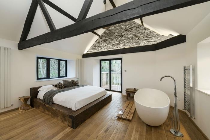 dekorácia spálne s otvorenou kúpeľňou drevené parkety voľne stojaca vaňa biely strop s čiernymi drevenými trámami