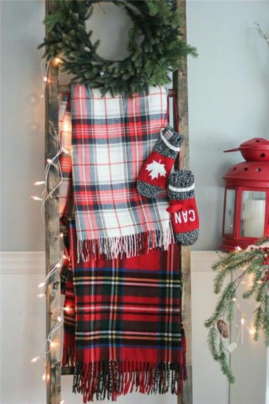 Vianočné remeslá, jednoduchá vianočná ozdoba vlastnoručne vyrobená, s rebríkom, opretým o stenu, dve šatky s červenými, čiernobielymi kármi, veniec zo zelených jedľových listov, dve rukavice v sivej a červenej farbe, malé svetlo v červenej farbe, ozdobený rebrík s rozprávkovými svetlami