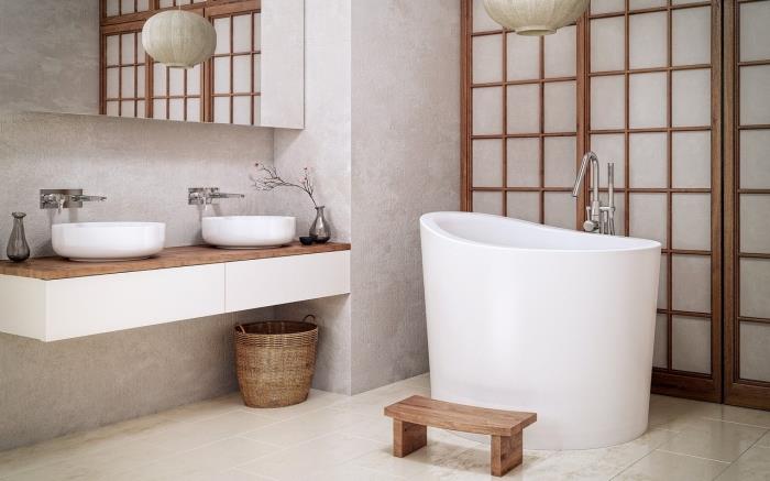 Ázijský dizajn kúpeľne v bielej farbe a dreve s malou voľne stojacou vaňou, kúpeľňová dekorácia so svetlosivými stenami s drevenými akcentmi
