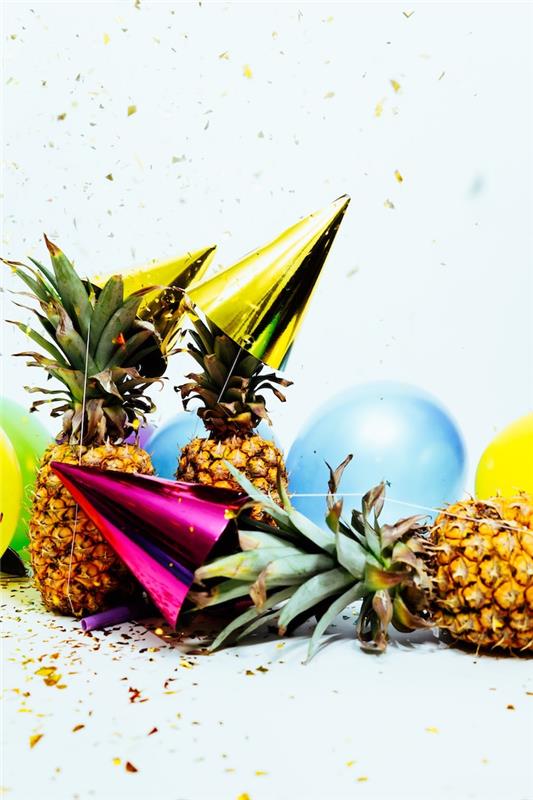 ananas decp för nyårsdagen med ananas, färgglada ballonger och festmössor omgiven av regn av konfetti