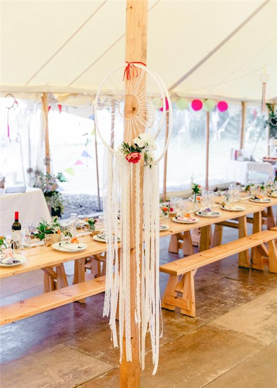 biely svadobný stan s dreveným stolom a lavicami a ozdobou lapača snov, bohémsky elegantný svadobný dekor