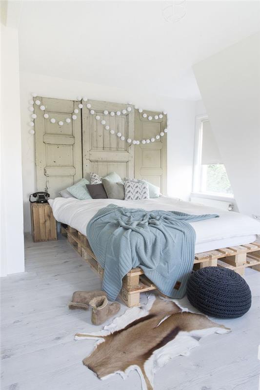 príjemná spálňa v škandinávskom štýle, ktorá preberá rekultivovaný trend, s európskou paletovou posteľou a starým čelom k dverám