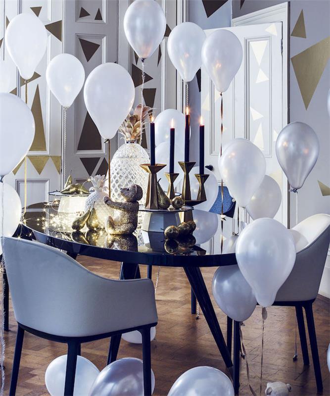 svart bord, guldljus med svarta ljus, ljus krans och dekorativa ananas, vita ballonger och väggar dekorerade med gyllene trianglar, elegant nyårstema