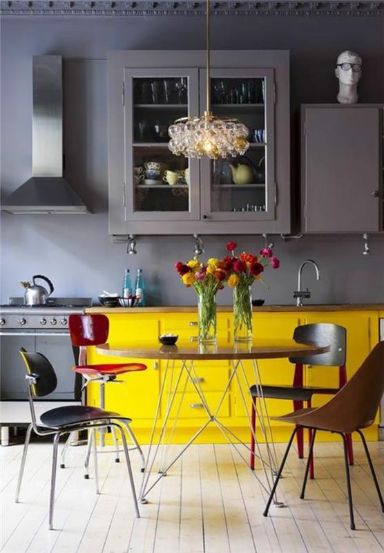 kačacia modrá kuchyňa, kačacia modrá farba, štyri stoličky rôznych farieb okolo stola, béžová parketová podlaha, neoklasicistické vlysy na strope