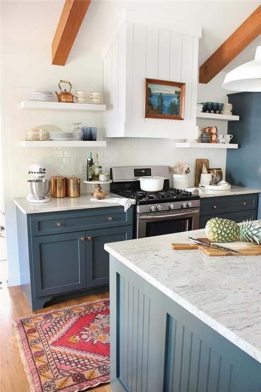 modrá kuchyňa so svetlo hnedými trámami na bielom strope, farebný koberec s bielymi strapcami, nábytkové pracovné dosky s mramorovanými efektmi, leštené béžové parkety