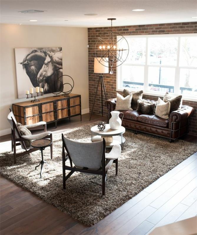 blandning av country chic, industriell och rustik inredning, tegelvägg, grå matta, trä- och tygstolar, brun skinnsoffa, soffbord, trägolv, designerlampa, ljuskrona, hästritning väggdekoration