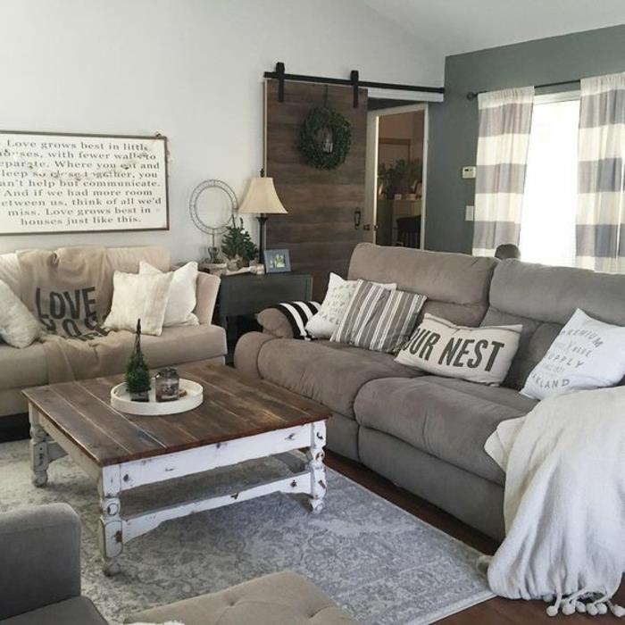 elegant lantlig inredning med industriell charm. soffbord i trä, grå matta och soffor, rustik trädörr, vintage väggdekorativ panel