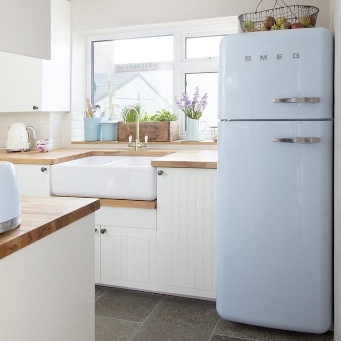 ديكور المطبخ الريفي مع بلاط خرساني وخزانة مطبخ بيضاء وثلاجة زرقاء فاتحة وسطح عمل خشبي وبلاط أبيض
