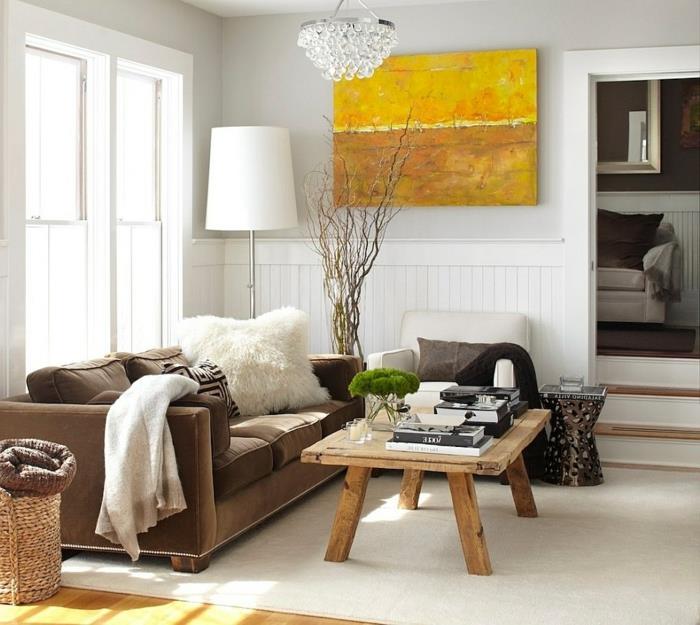 modern vardagsrumsdekoration med ett rustikt soffbord i skandinavisk charm, brun soffa, vit fåtölj, gul bordsväggdekoration, designerupphängning, vitvit matta