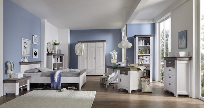 غرفة نوم مراهقة داخلية بجدران بيضاء وزرقاء فاتحة وأثاث خشبي مطلي باللون الأبيض وبساط مستطيل رقيق