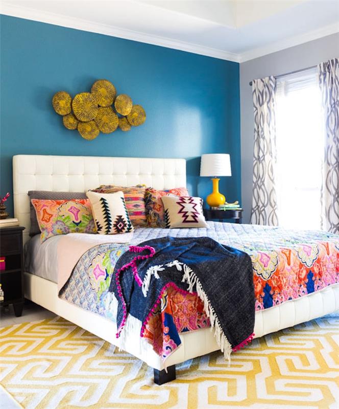 výzdoba hlavnej spálne s modrou stenou, farebná posteľná bielizeň s kvetinovými vzormi, bohémsky elegantný štýl, biely a žltý koberec