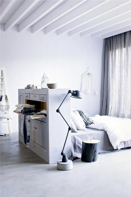 vitt sovrum, säng med sänggavel som fungerar som rymdavdelare, stora vitmålade balkar, grå parkett, svart metallfällbart ljus i industriell stil, halvtransparenta gardiner i ljusgrått