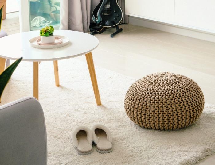 minimalistický dizajn obývačky v bielej farbe s drevenými akcentmi, okrúhly a nízky model stolu do obývačky, nápad na biely a mäkký koberec do obývačky