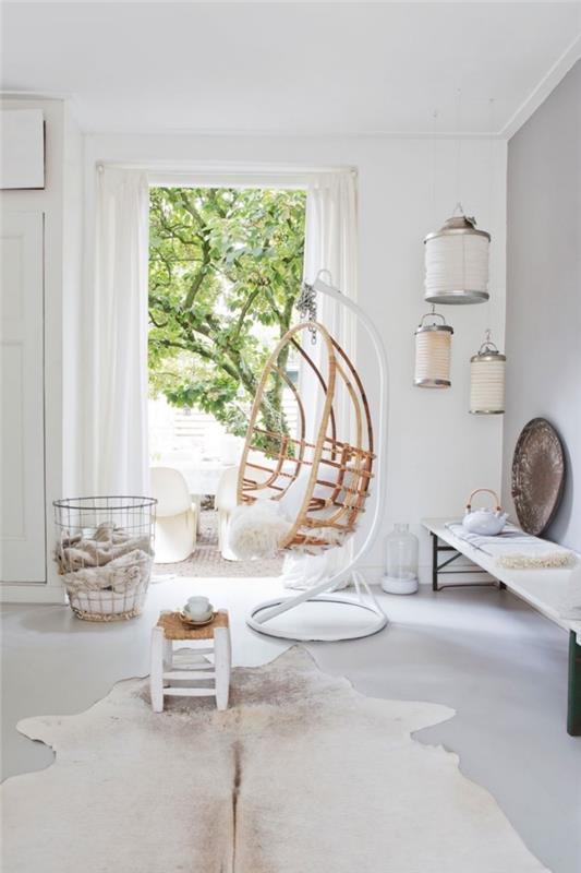 obefläckat vitt vardagsrum med etnisk chic inredning accenter med en hängande stol accessorized med ett skandinaviskt fårskinn för en mysig och avkopplande atmosfär