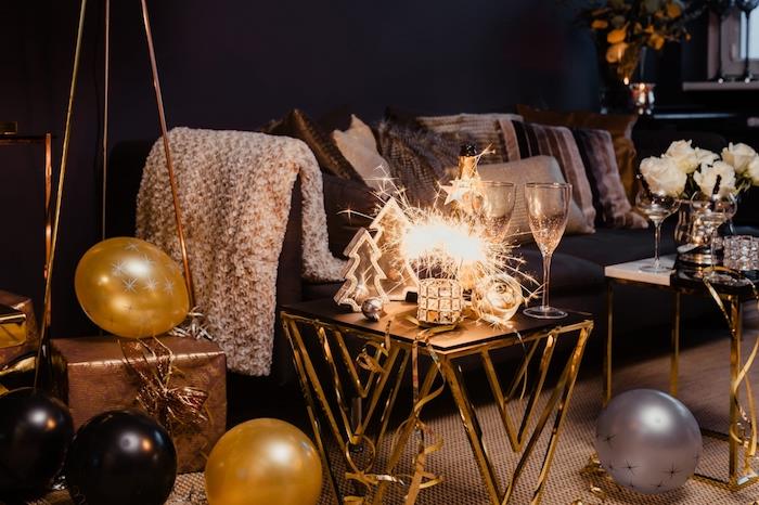 Nyårsdekoration för ett kokande och festligt vardagsrum, guld- och svarta ballonger, julgranfigurer, bukett vita rosor