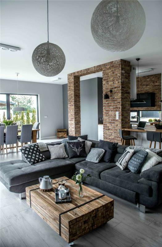 samtida deco modernt rustikt och industriellt vardagsrum, tegelportal, soffbord i plywood på hjul, koksgrå soffa, grått laminatgolv, kök och matplats, original hängande lampor