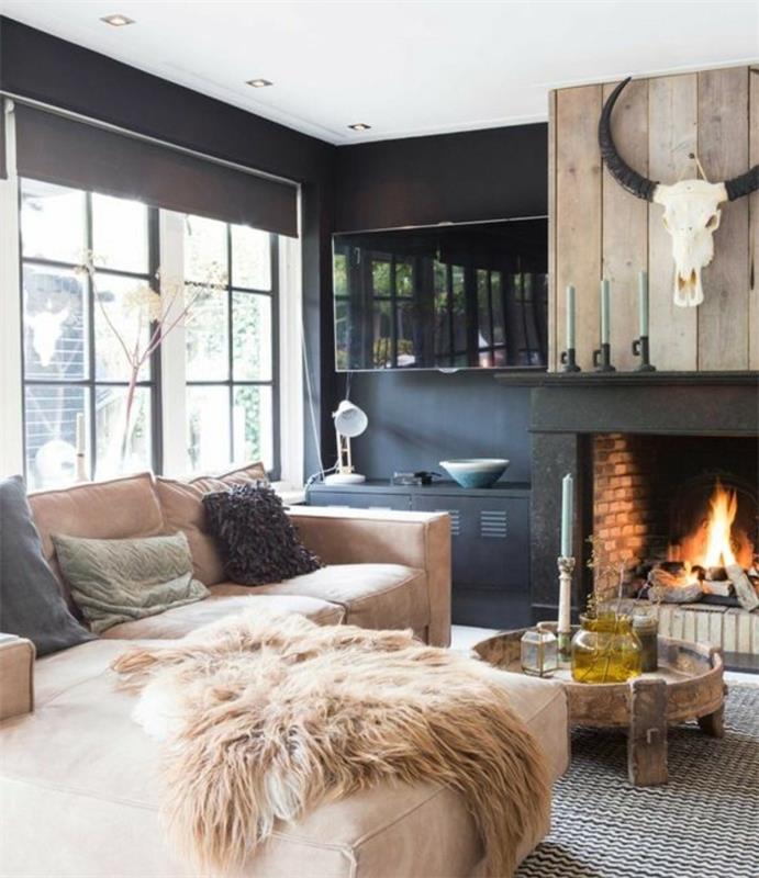 rustikt vardagsrum, svartvit matta, fawn hörnsoffa, soffbord i trä, romantisk öppen spis, svartfärgade väggar och vitt tak, troféväggdekoration, träverk
