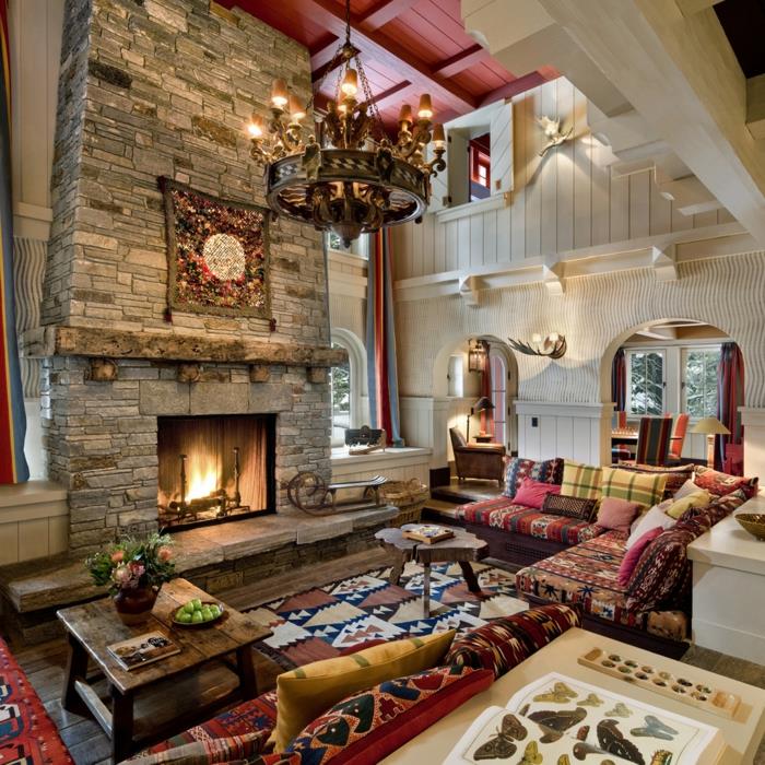 modern rustik bohemisk inredning, vardagsrum med öppen spis, indianmönstrad matta, etnisk soffa med mångfärgade kuddar, soffbord i rått trä, original ljuskrona