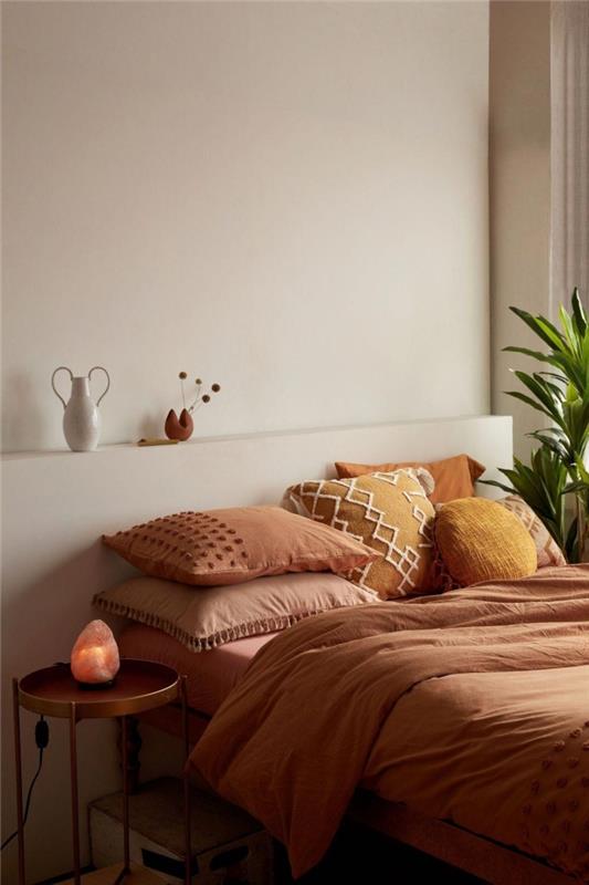 dekoratívna farba terakotový dizajn spálňa boho minimalistický okrúhly kovový stôl čedar žltý vankúš s výšivkou macrame pom poms