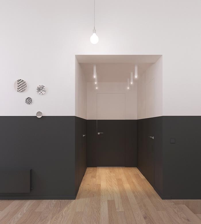 grafisk korridordekoration med tvåfärgade väggar målade halvvägs upp i kolgrått med en matt yta i kontrast till det parkett av blont trä