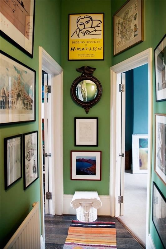 Deco úzka chodba natretá zelenou farbou so stenami v rôznych rámoch na fotografie a bielymi dverami