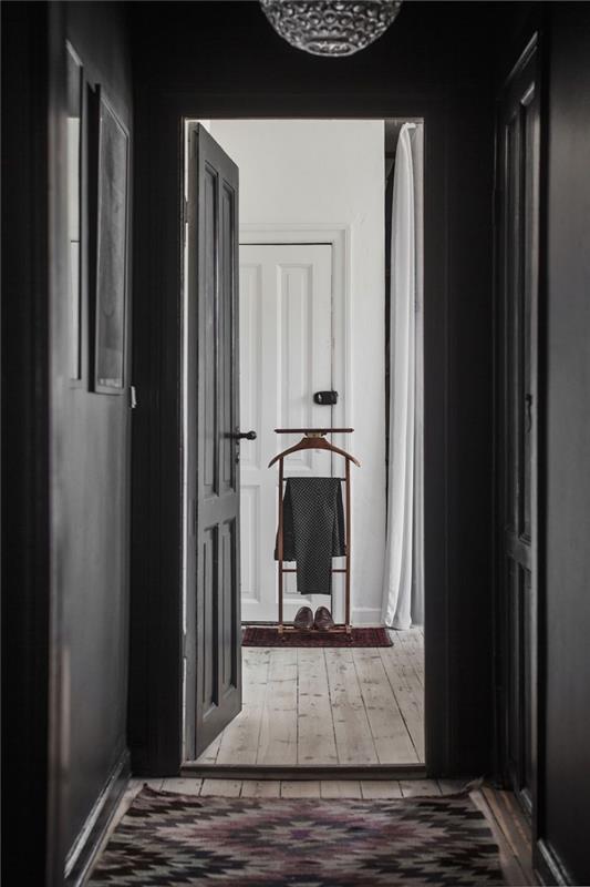 triezva výzdoba chodby v škandinávskom štýle so stenami a dverami natretými rovnakou matnou čiernou farbou na rozdiel od bieleho interiéru