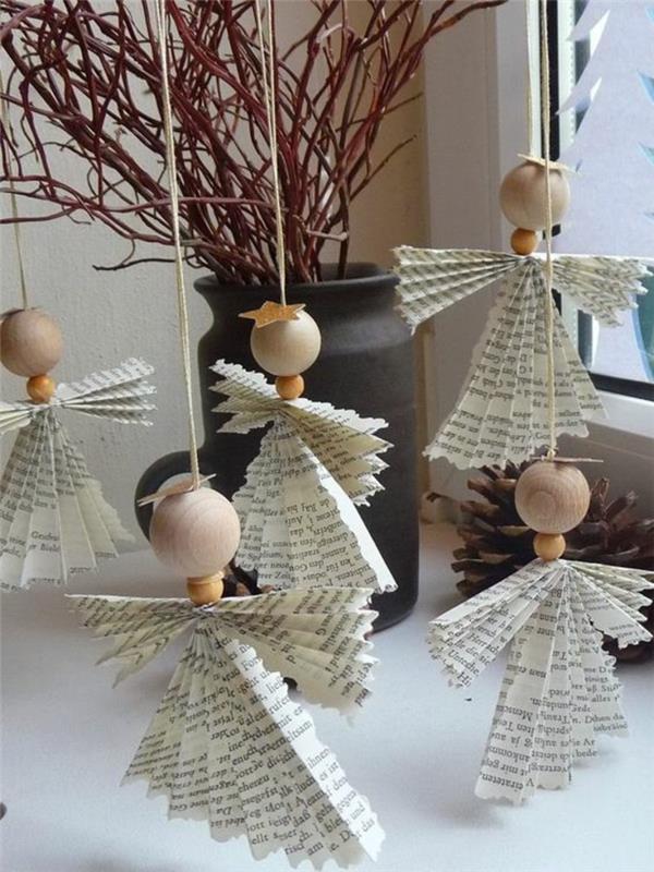 Vianočná manuálna aktivita s plisovanými papierovými anjelmi s roztiahnutými krídlami, s hlavicami zo svetlého dreva, ozdobnou čiernou keramickou vázou