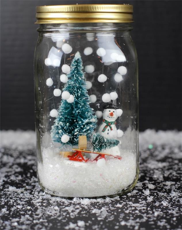 ručne vyrobená vianočná ozdoba z recyklovaných sklenených pohárov a vianočných figúrok, DIY bezvodá snehová guľa s falošným snehom visiaca z veka