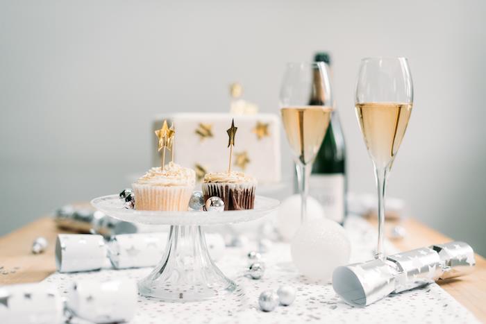 konfettikanoner, vit bordslöpare med silverstjärnor, muffins på serveringsbricka, champagneglas