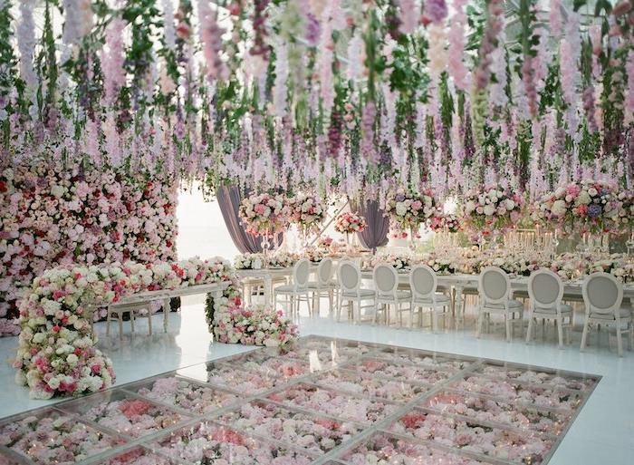 kvetinová svadobná téma s kvetmi visiacimi zo stropu, kvetinovej girlandy a podlahy s kvetmi pod baldachýnom