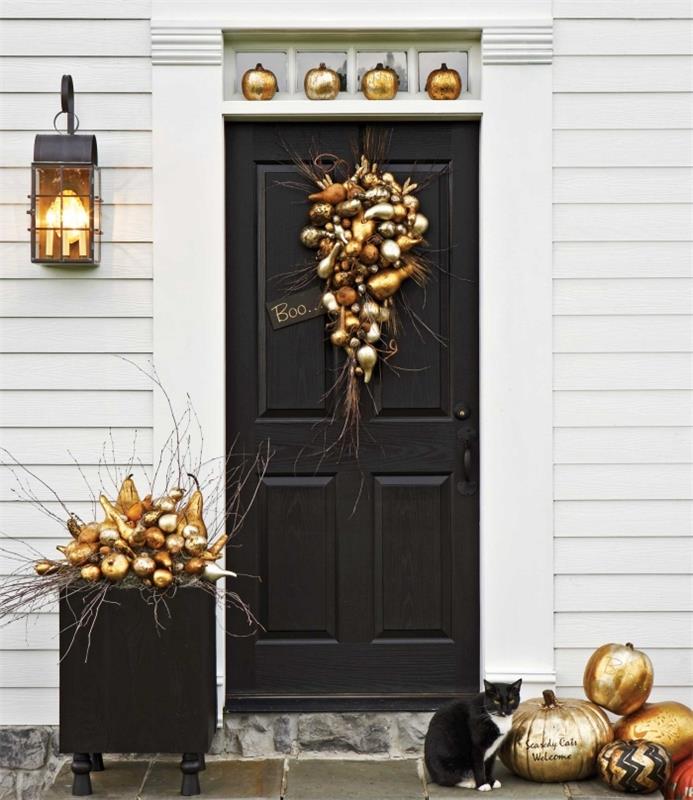 DIY halloween, svart ytterdörrsdekoration med frukt och grönsaker målade i guld och orange, svart lykta med gul lampa