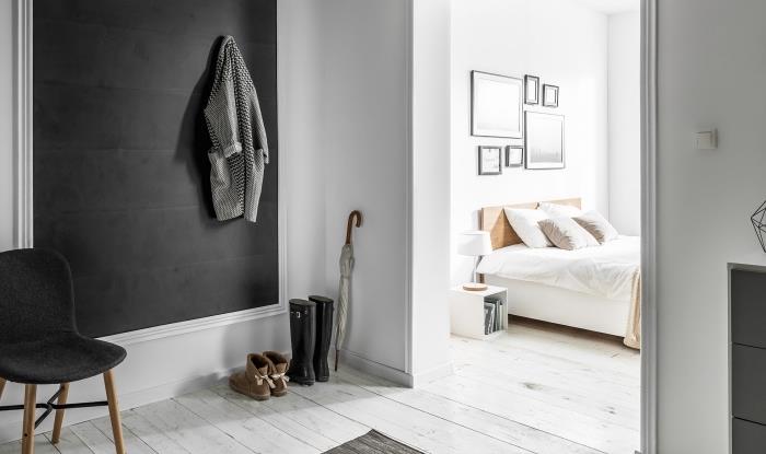 minimalistisk anda i en hall och sovrum med vita väggar och ljus träparkett med mörkgrå väggdel