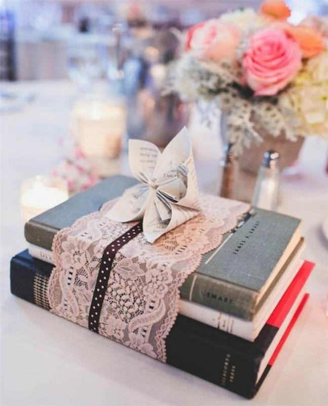 högar med böcker, inslagna i rosa spetsband, bukett blommor, ljusstakar, bröllopstillfälle deco -idé