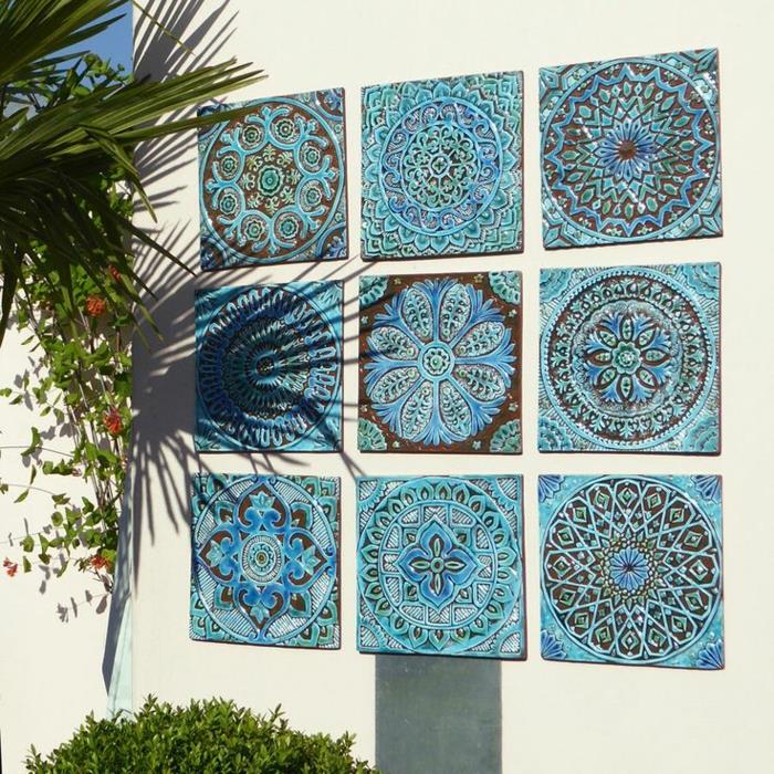 mozaika v modrej a čiernej farbe vložená do steny v exteriérovej krémovej bielej farbe, ozdobte vonkajšiu záhradnú stenu mandalovými vzormi, deväť mozaikových mandál