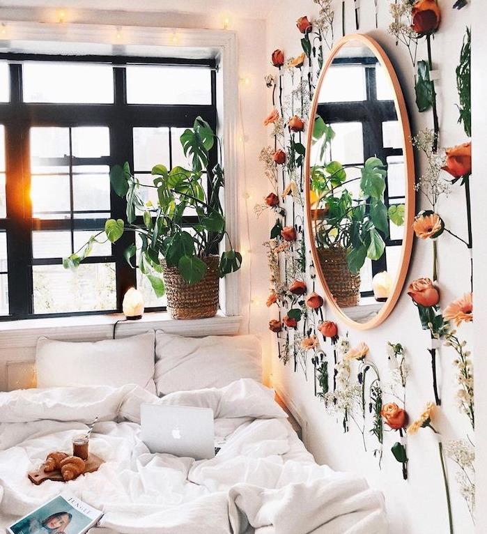 tropická rastlina na parapete a v interiéri zelená stena vetvičiek kvetov okolo okrúhleho zrkadla, romantická výzdoba spálne