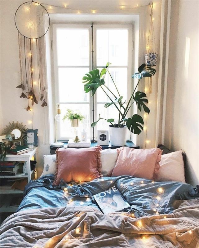vacker sovrumslayout, rosa kuddar, gråa sängkläder, vit blomkruka med grön växt, fönster, drömfångare, ljus krans