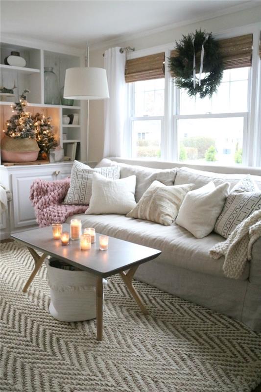 cocooning semesterinredning i en skandinavisk och traditionell festlig anda med en mjuk soffa dekorerad med kuddar, ett soffbord dekoration av ljus och en vacker julgran i en korg
