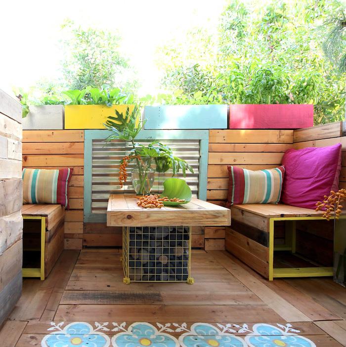deco drevená terasa s konferenčným stolíkom v gabióne z ľahkých paliet a malými lavicami, rastliny v pestrofarebných kvetináčoch
