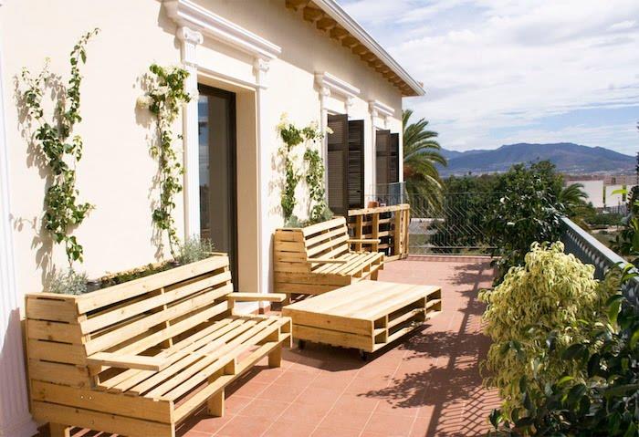 patio dekorácia s paletovým záhradným nábytkom s paletovou lavicou a paletovým dreveným konferenčným stolíkom, hnedá dlažba